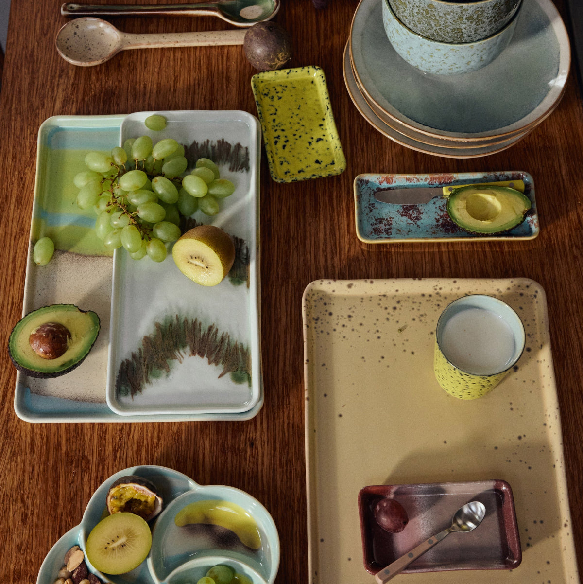 Table setting with ceramic plates, bowls, and utensils on a wooden surface.