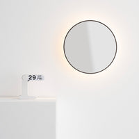 A white modular calendar displayed next to a round mirror with a light fixture on a white wall