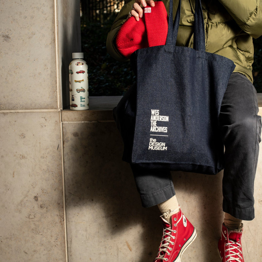 Person sitting on a wall with a navy tote bag, red shoes, and a white water bottle.