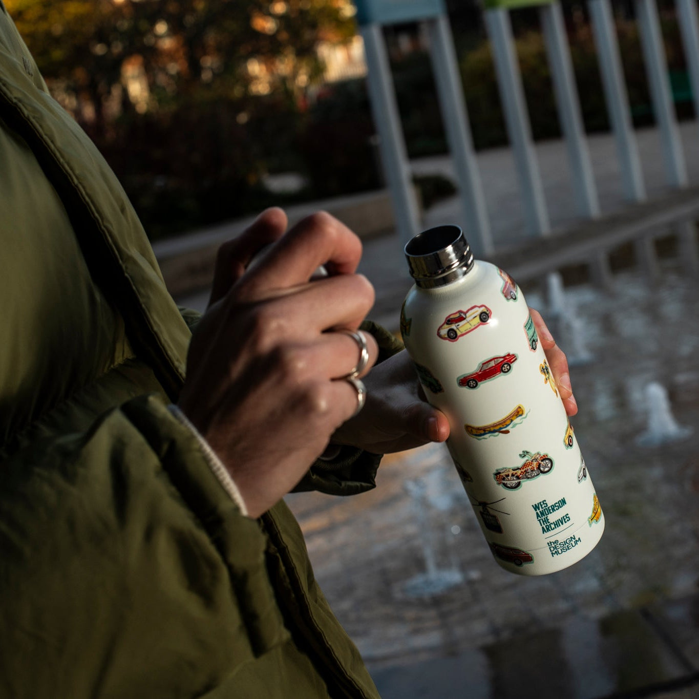 Person holding a white water bottle with vehicle illustrtaions outdoors