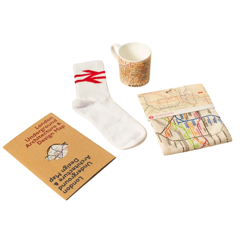 A flat-lay collection of transport-themed items including a white rail logo crew sock , a ceramic mug with a map print, and a folded map pouch