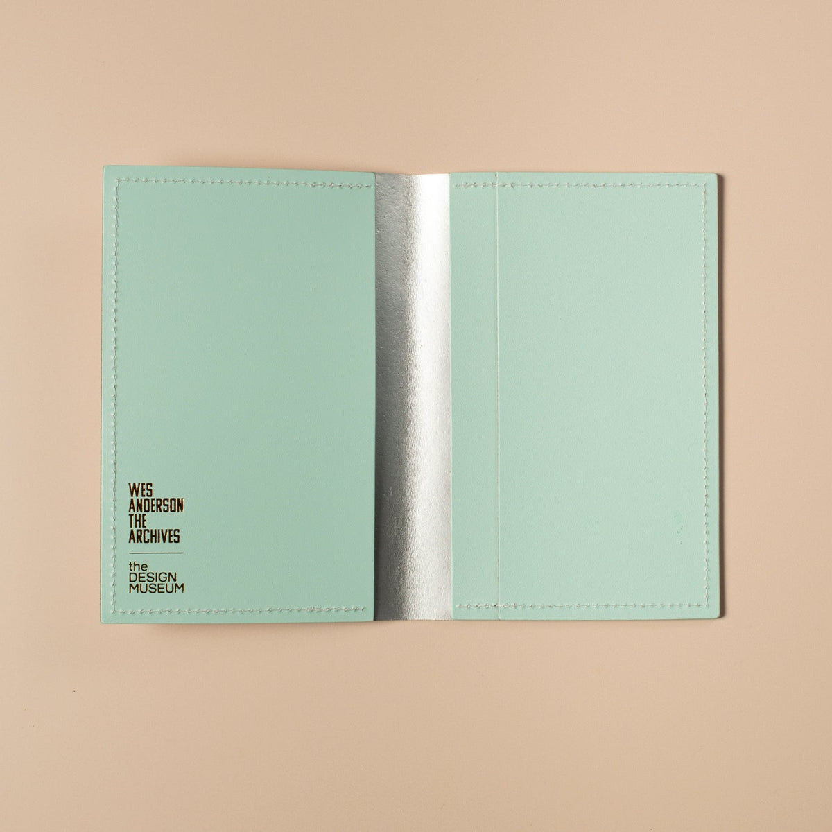 Open light blue passport holder with brand name on a beige background