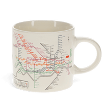A ceramic mug with a white background featuring a vintage print of London's underground map in colorful lines.