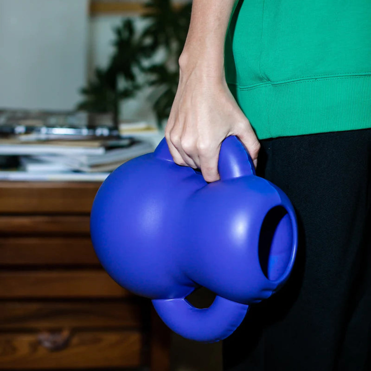 Person holding a blue inflatable ceramic vase with  handles.