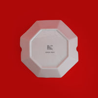 White octagonal trinket dish on a red background