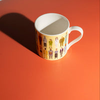 Yellow mug with illustrated characters on an orange surface