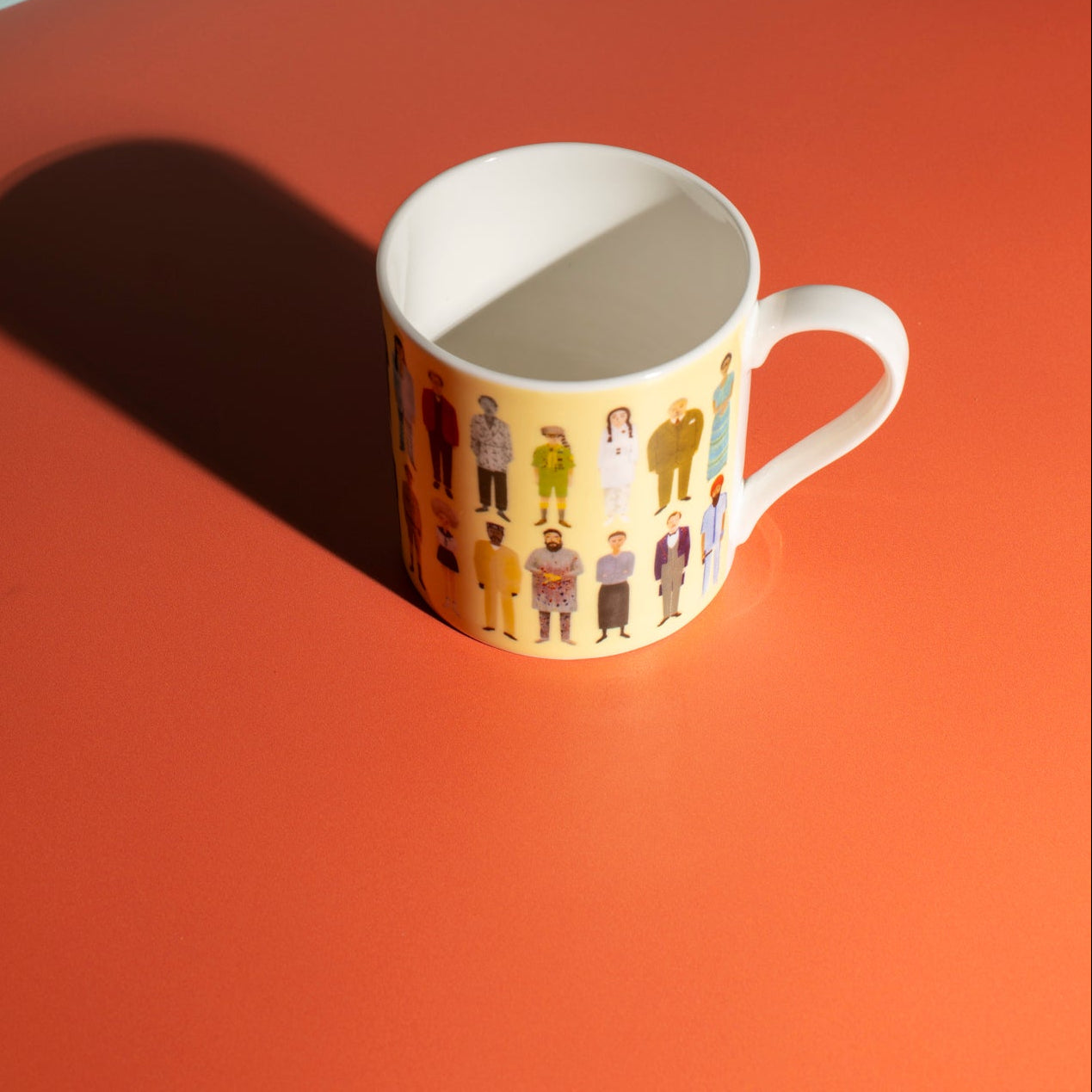 Yellow mug with illustrated characters on an orange surface