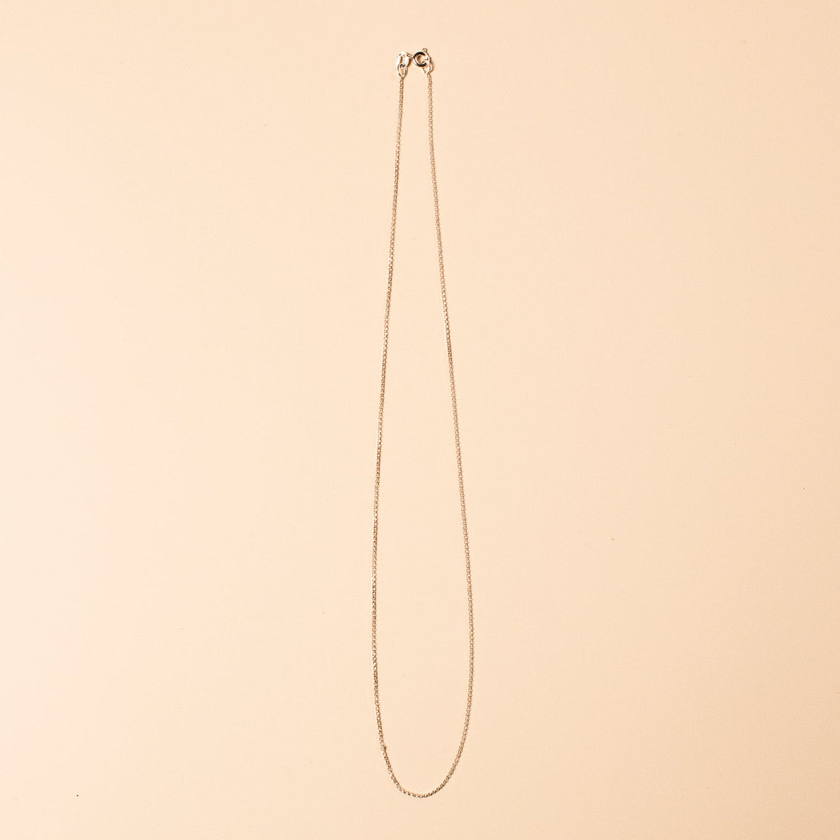 Silver necklace chain on a beige background