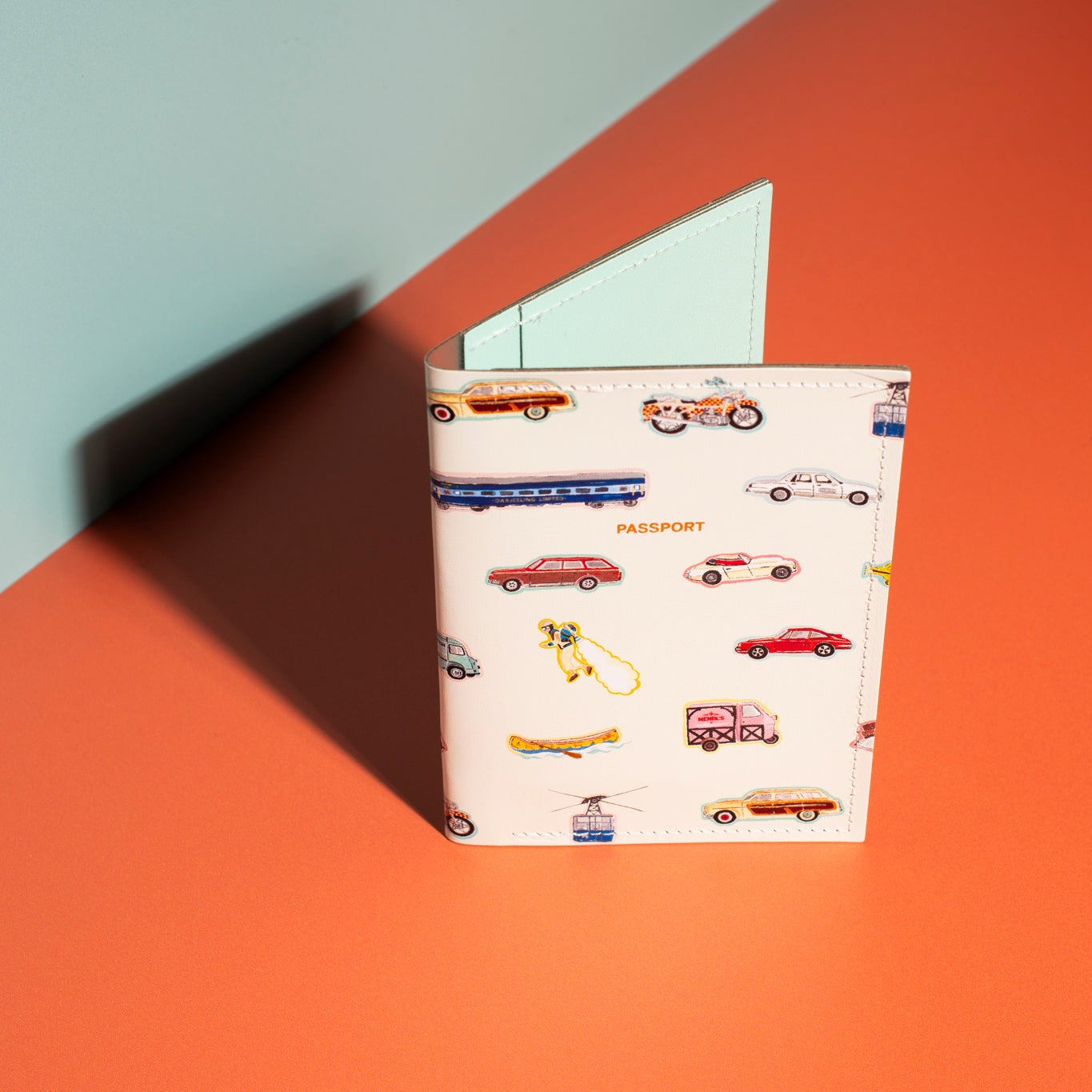 A white passport holder with vehicle illustrations on a red and blue background