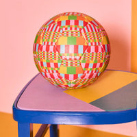 Colourful checkered ball on a multicolored chair with a pink background