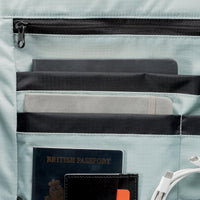 Light blue interior of a backpack with compartments holding a British passport, card, and cable.