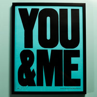 Framed artwork with 'YOU & ME' in bold black text on a light blue background