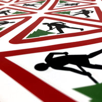 Close up of Margaret Calvert wrapping paper with a cartoon person holding a christmas tree inside a red triangle.