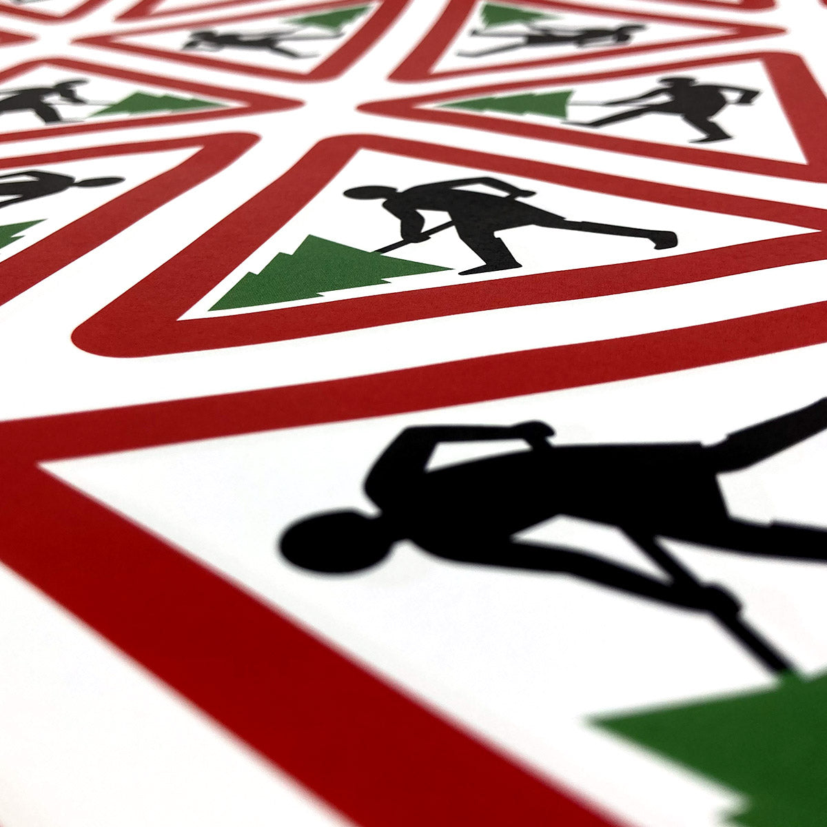 Close up of Margaret Calvert wrapping paper with a cartoon person holding a christmas tree inside a red triangle.