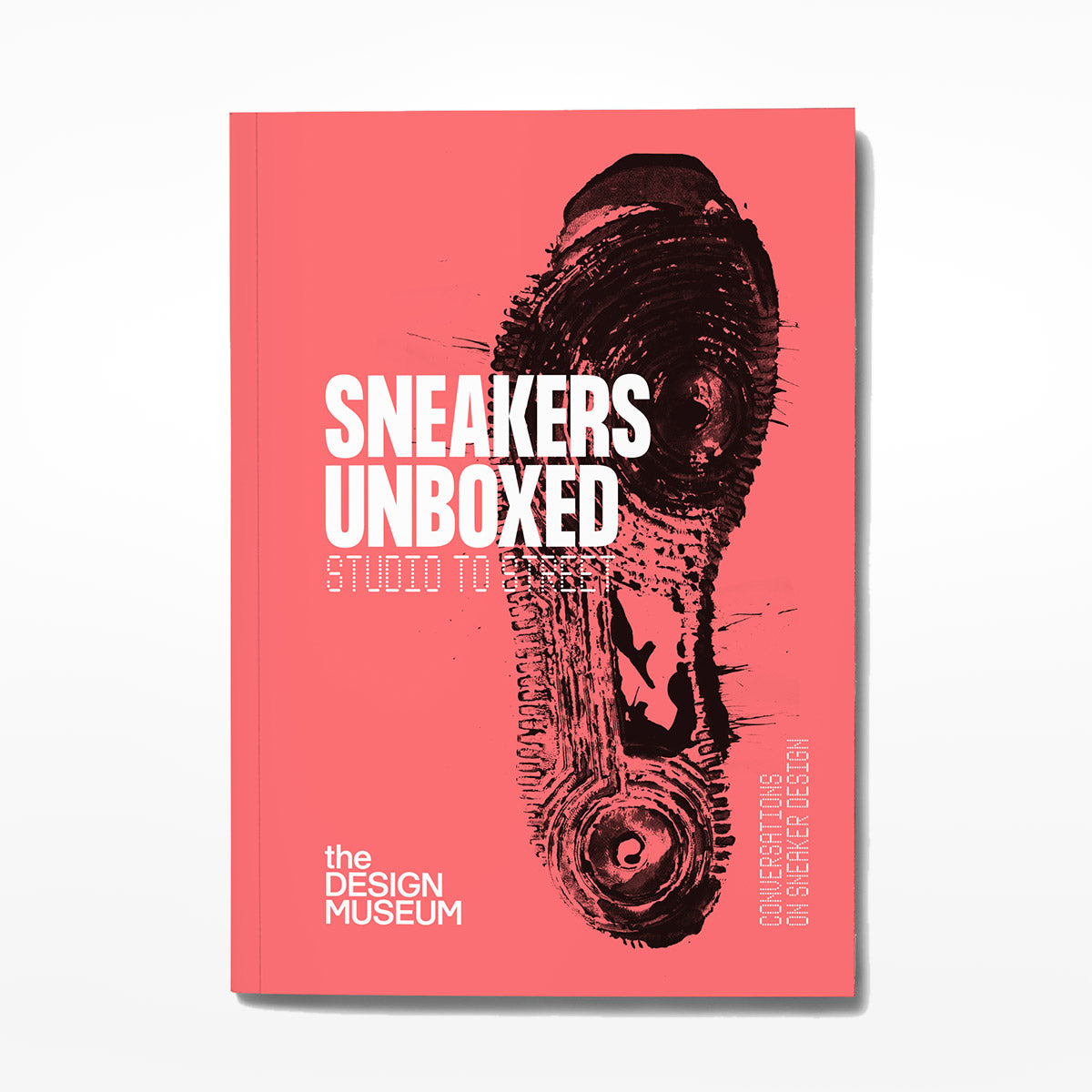 Red front cover of Sneakers Unboxed Exhibition Catalogue with black footprint on a white background.