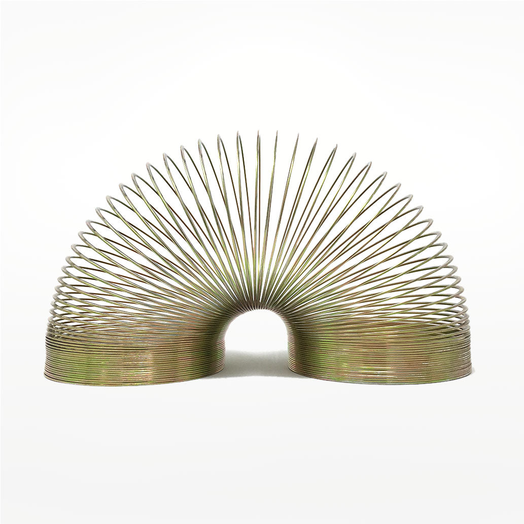Gold coloured metal slinky on a white background